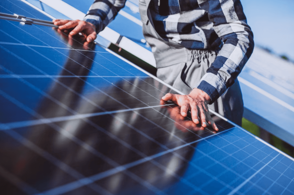 Homem com as mãos apoiadas em uma placa de energia solar.