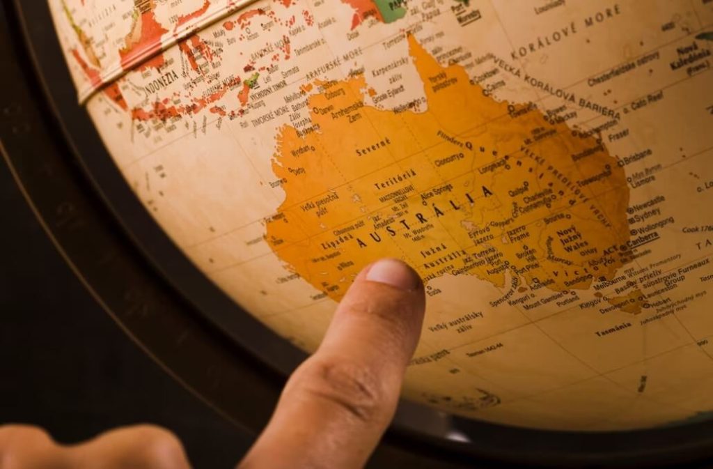 Dedo indicador apontando para a Austrália em um globo.