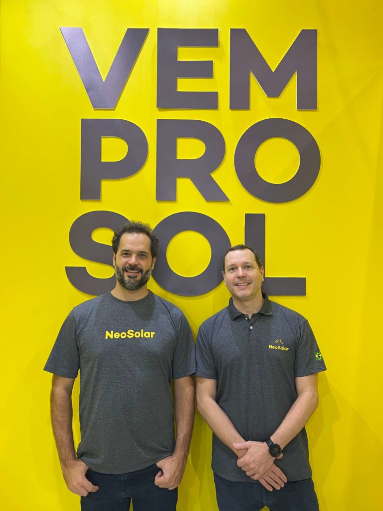 Raphael Pintão e Pedro Pintão, os sócios-fundadores da NeoSolar, em frente a uma parede da sede da empresa.